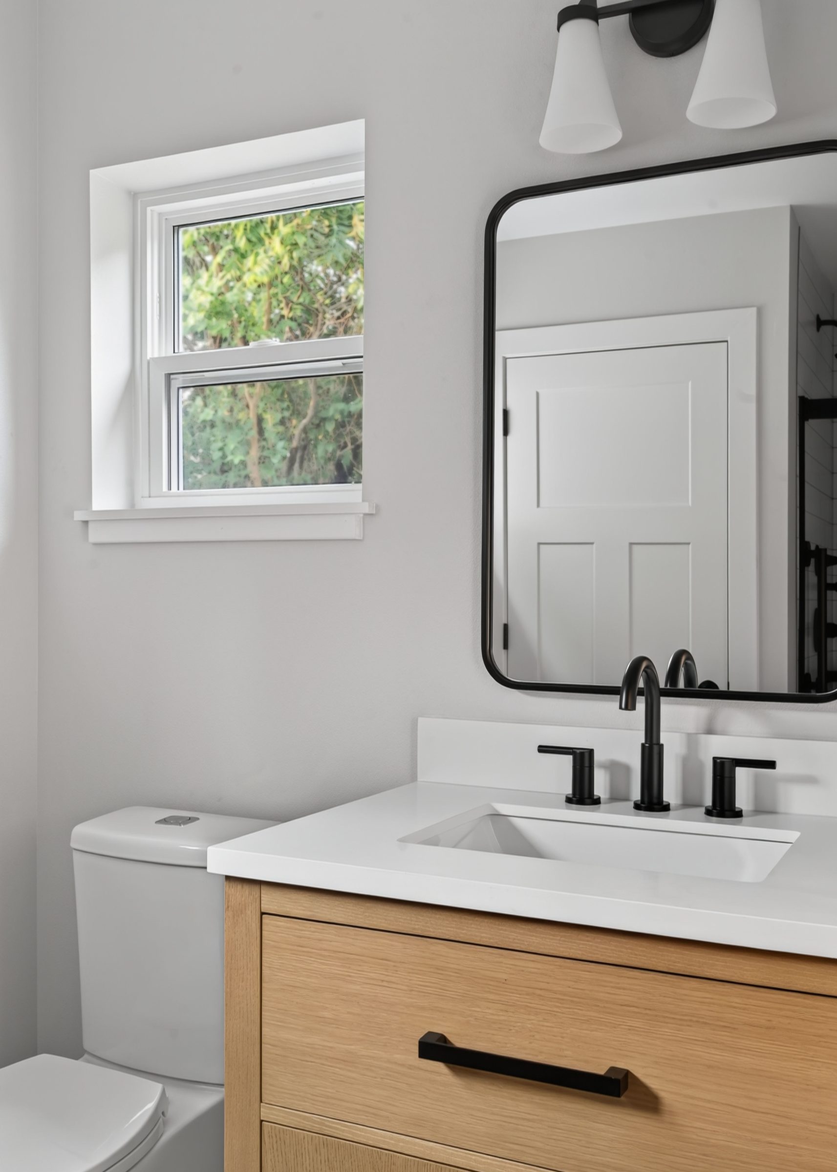 Wood-tone vanity, black faucet, and a window for natural light — aging-in-place ADU, Madison WI