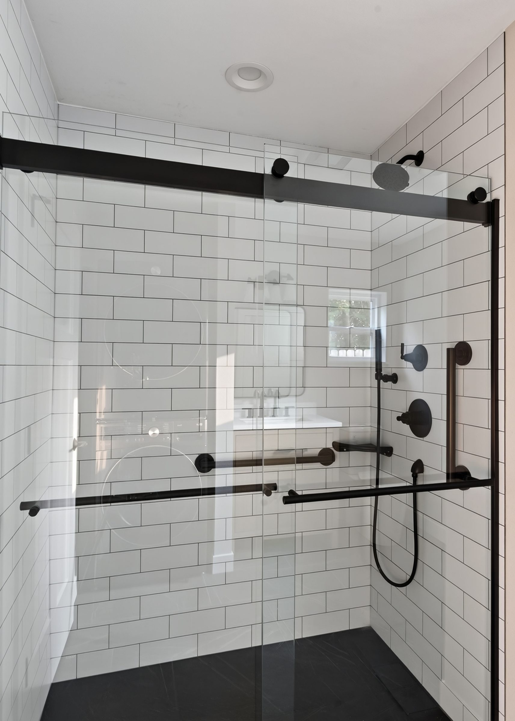 Curbless walk-in shower with grab bars and a sliding glass door — aging-in-place ADU, Madison WI