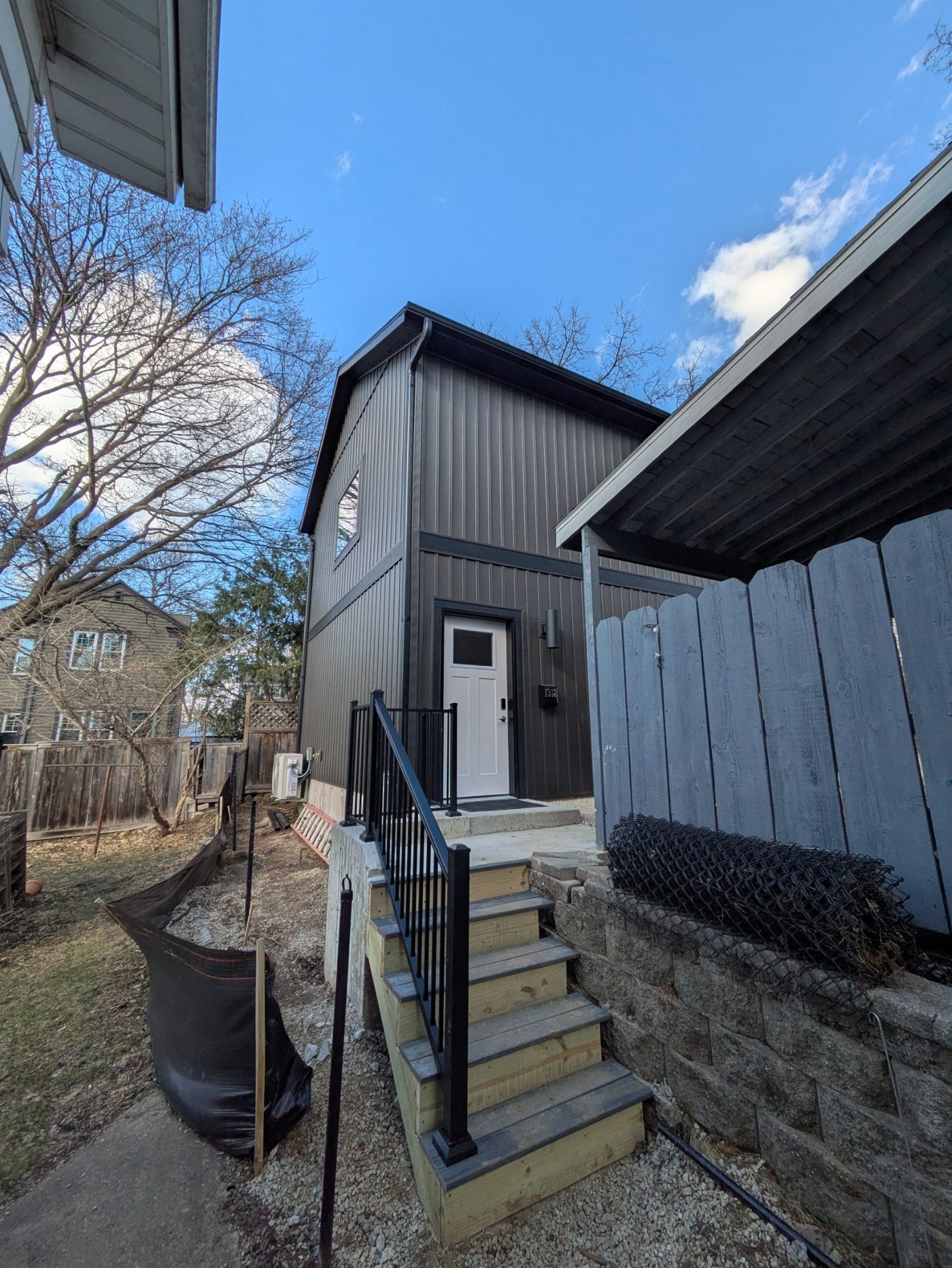 Completed tenant entry staircase with black metal railings and white front door — Henry Vilas ADU Madison WI