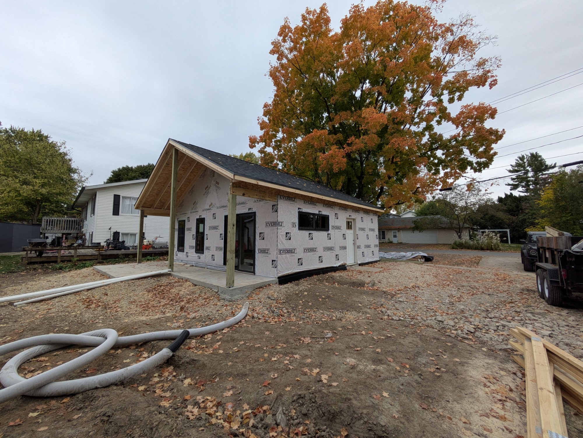 Roof on and windows set with fall foliage — North Side ADU Madison WI, October 2025