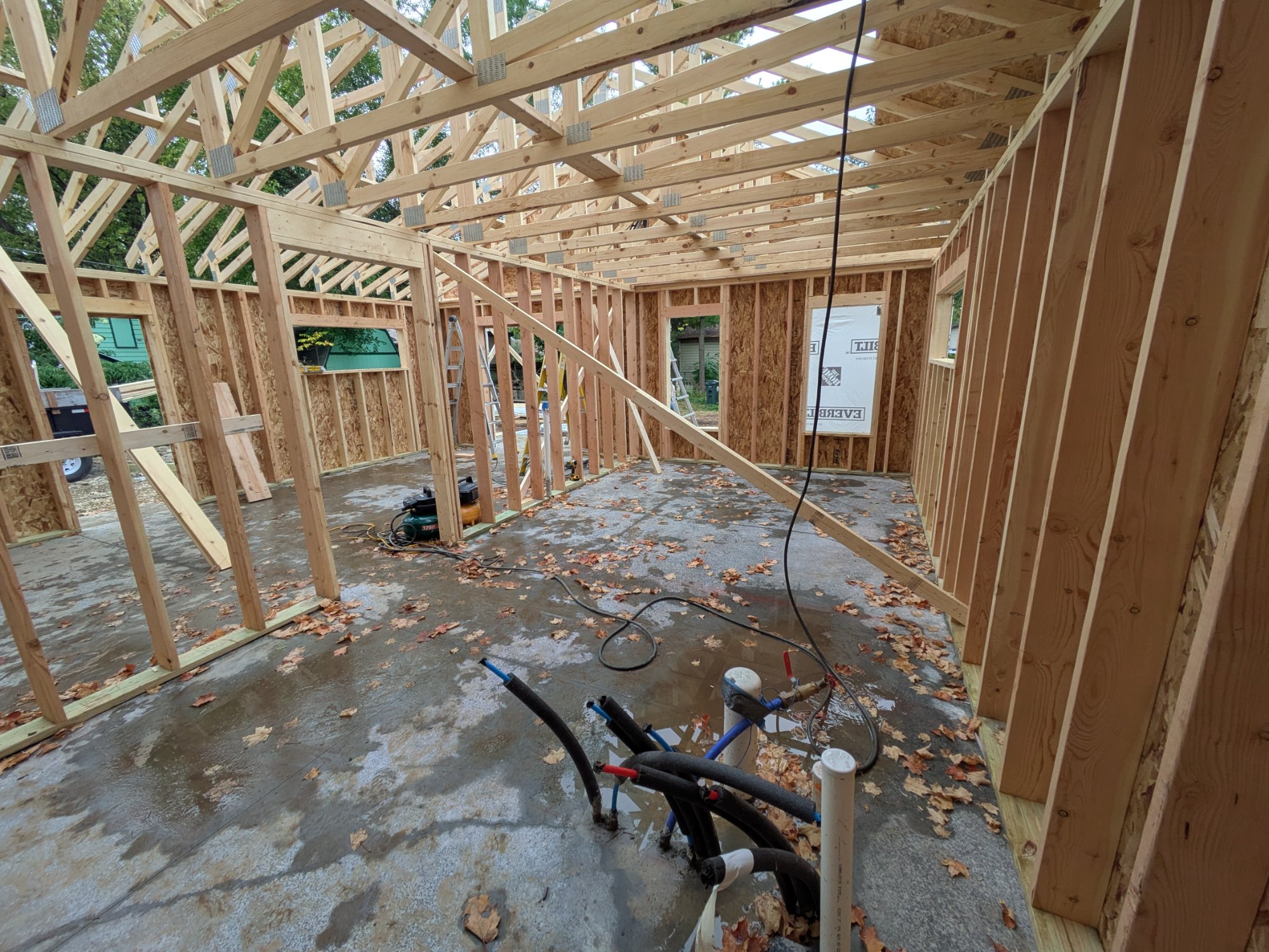 Interior framing with vaulted trusses and plumbing rough-in on slab — North Side ADU Madison WI